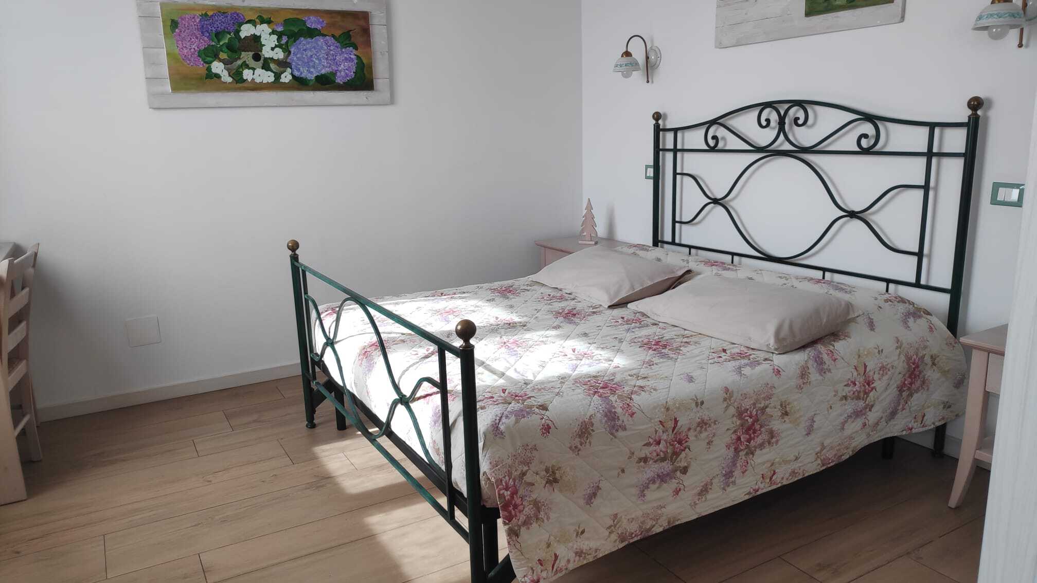 Letto matrimoniale con copriletto floreale nella Camera Lilla