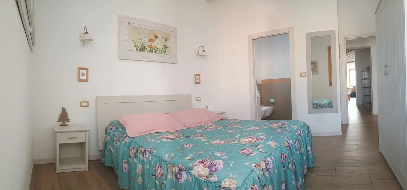 Letto matrimoniale con copriletto floreale nella Camera Mimosa